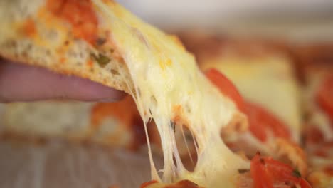 hand picks up slice of pizza, cheese stretching, slow motion side view