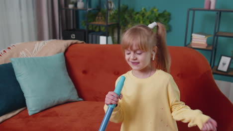 Una-Niña-Pequeña-Graciosa-Limpiando-Pisos-Con-Un-Trapeador-En-Casa-Bailando,-Cantando-De-Humor-Positivo