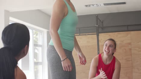 unaltered diverse women motivating determined woman jumping on boxes at fitness class, slow motion