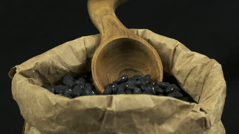 frijoles de tortuga negra en una bolsa de papel con una cuchara de madera funky, en primer plano