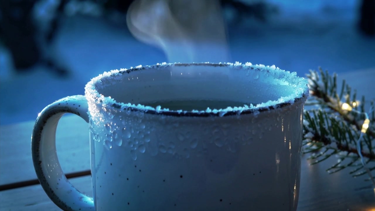 Taza moteada humeante, líquido caliente encontrándose con el aire frío del anochecer en un bosque nevado, con una ramita de hoja perenne iluminada.
