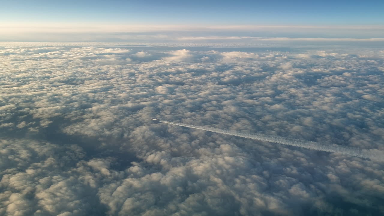 vista increíble desde la cabina de un avión que vuela alto por encima de las nubes dejando un largo rastro de aire de vapor de condensación blanco en el cielo azul