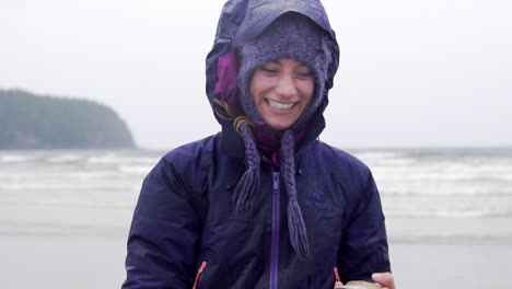 happy girl running and enjoying life with a shelf in her hand witch is found a the beach on a drizzly summer day in tofino slowmotion shot