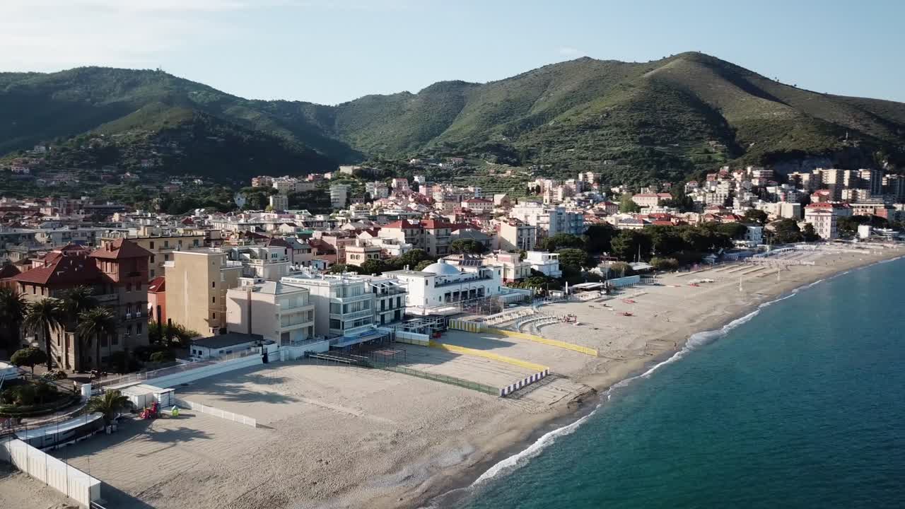 toma panorámica con drones: playa de arena, agua azul y montañas