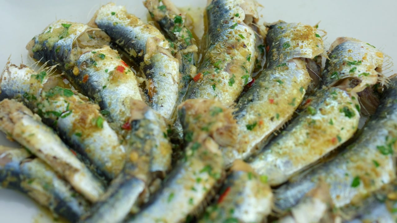 Gotowane sardynki przygotowane ze świeżą natką pietruszki, czosnkiem, chili i oliwą z oliwek, podawane jako pyszna śródziemnomorska przystawka