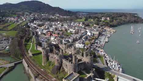 Eine-Luftaufnahme-Von-Conwy-Castle-An-Einem-Sonnigen-Tag,-Wegfliegend-Vom-Schloss-Mit-Der-Stadt-Im-Hintergrund,-Nordwales,-Großbritannien