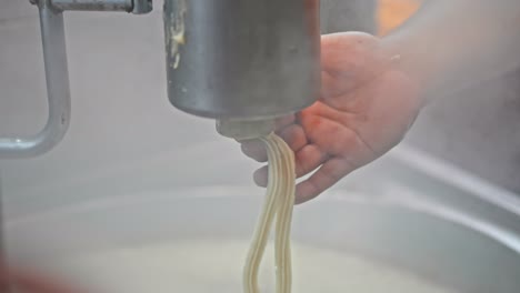 Close-up-on-man's-hand-while-making-churros,-typical-Spanish-sweet-fried-dough