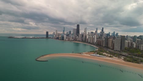 Aerial-pan-of-North-Avenue-Beach-Pier-and-Chicago-skyline,-Hancock-Building