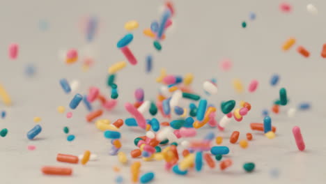 rainbow sprinkles falling on white back drop in extreme slow motion