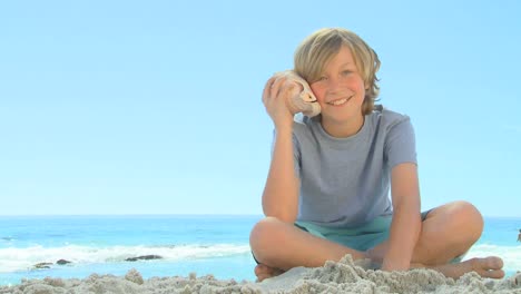 Young-smiling-boy-listening-to-a-shell