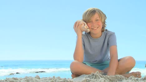 young smiling boy listening to a shell