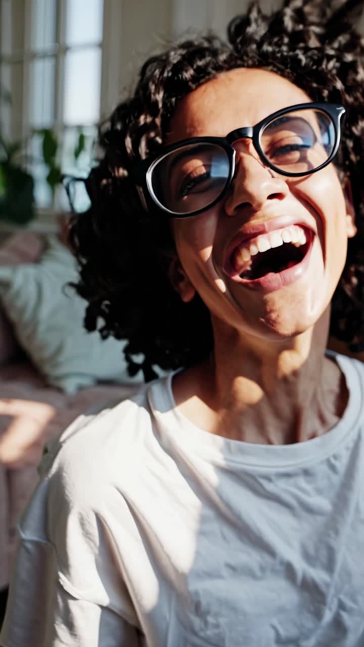 A joyful woman with curly hair and glasses, captured in a side profile with a close-up angle