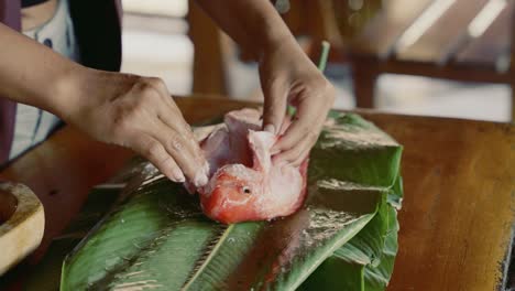 woman salting a fish before cooking