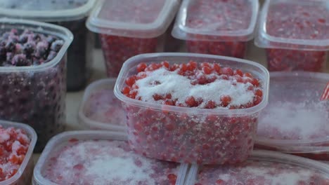 tablespoon sugar sprinkled on red currant berries in plastic containers