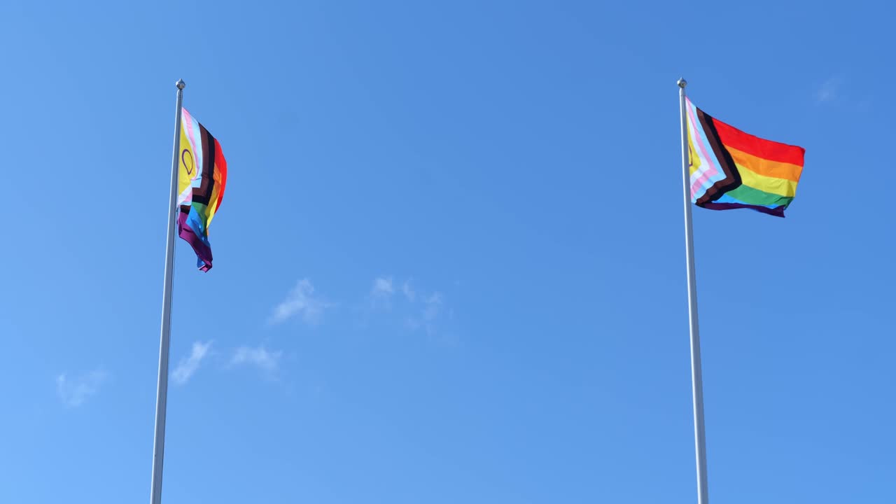 Two Vibrant Pride Flags Moving in Wind on Flagpole. Pride month concept.
