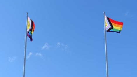 two vibrant pride flags moving in wind on flagpole. pride month concept.