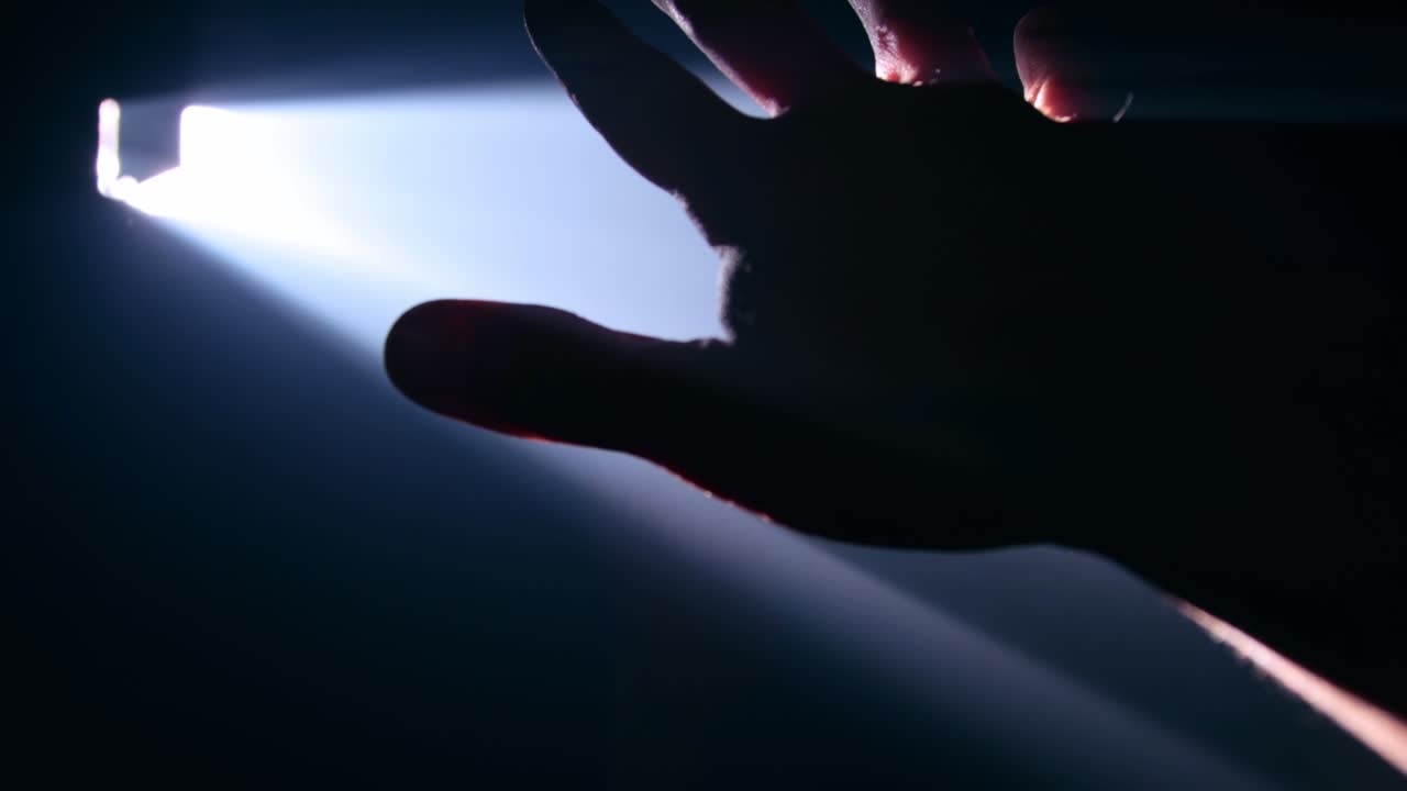 hombre sosteniendo su mano contra un rayo de luz