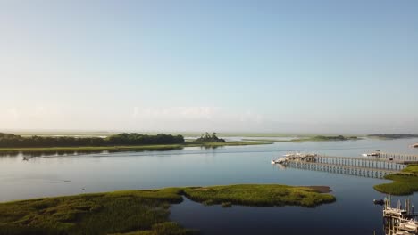 Peaceful-Sunrise-drone-takeoff-launch-over-piers,-waterway,-and-marsh-at-Trails-End-Park-in-Wilmington-North-Carolina