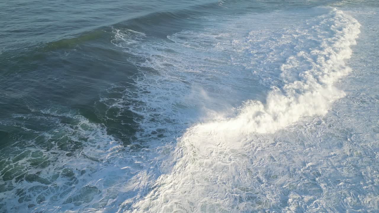 Waves crashing on the shore, aerial view of the ocean near Farol in Nazaré, Portugal