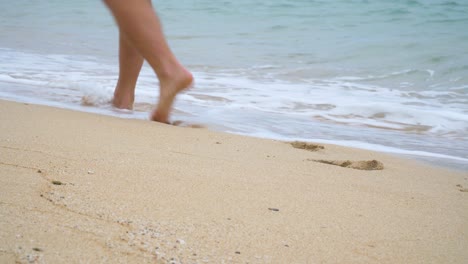 close up of mans feet walking on sandy beach next to water, stroll in paradise