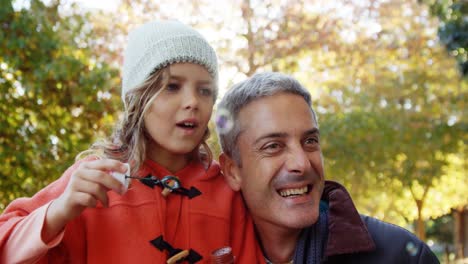 Niña-Soplando-Burbujas-Sostenidas-Por-Papá-Al-Aire-Libre