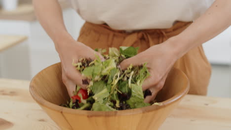 Nahaufnahme-Weiblicher-Hände,-Die-Salat-In-Einer-Holzschüssel-Mischen