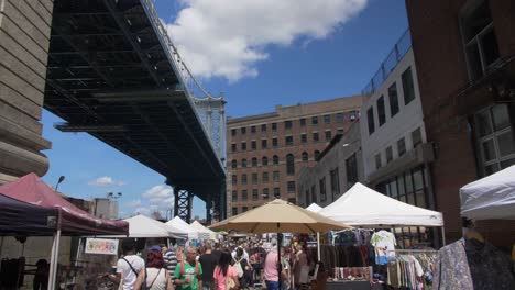 crowded street market underneath a bridge in new york city