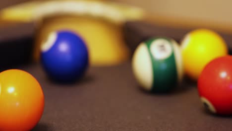 bola de rayas de colores golpeada por un jugador en el bolsillo de la esquina en el juego de billar