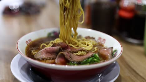 person eating ramen with chopsticks from a bowl