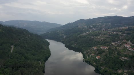 Toma-Aérea-Sobre-El-Agua-Del-Río-Douro-Bajo-Un-Atardecer-Azul-Con-Montañas-En-El-Fondo,-En-Baião,-Portugal