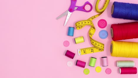 sewing and knitting items move on right side of pastel pink background. stop motion flat lay