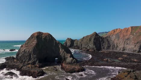 Filmischer-Drohnenschuss-Im-Tiefflug-Durch-Scharfe-Felsen-Vor-Der-Küste-Kaliforniens