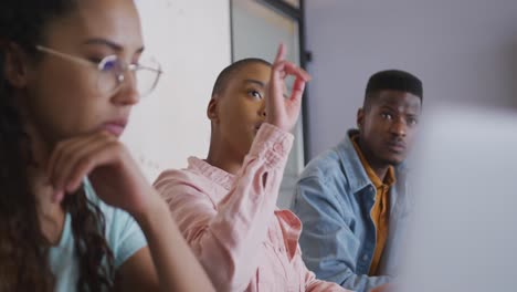 three diverse male and female creative colleagues listening and asking questions at meeting