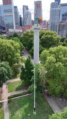 aerial view of a monument in a city park with skyscrapers in the background