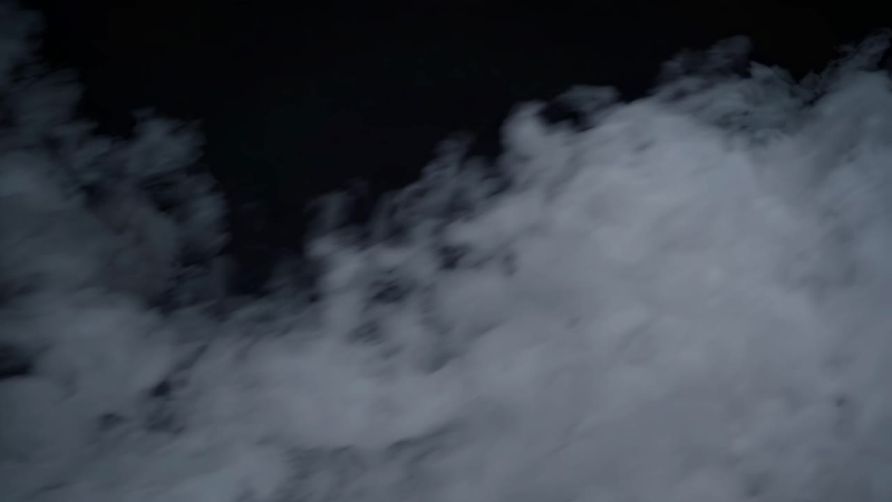 Vista aerea di fumo bianco vorticoso su sfondo scuro, che crea un'atmosfera misteriosa ed eterea.