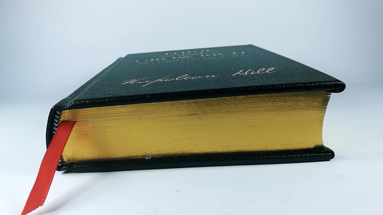 libro negro con páginas amarillas cerrándose lentamente aislado en un fondo blanco, slomo, quieto