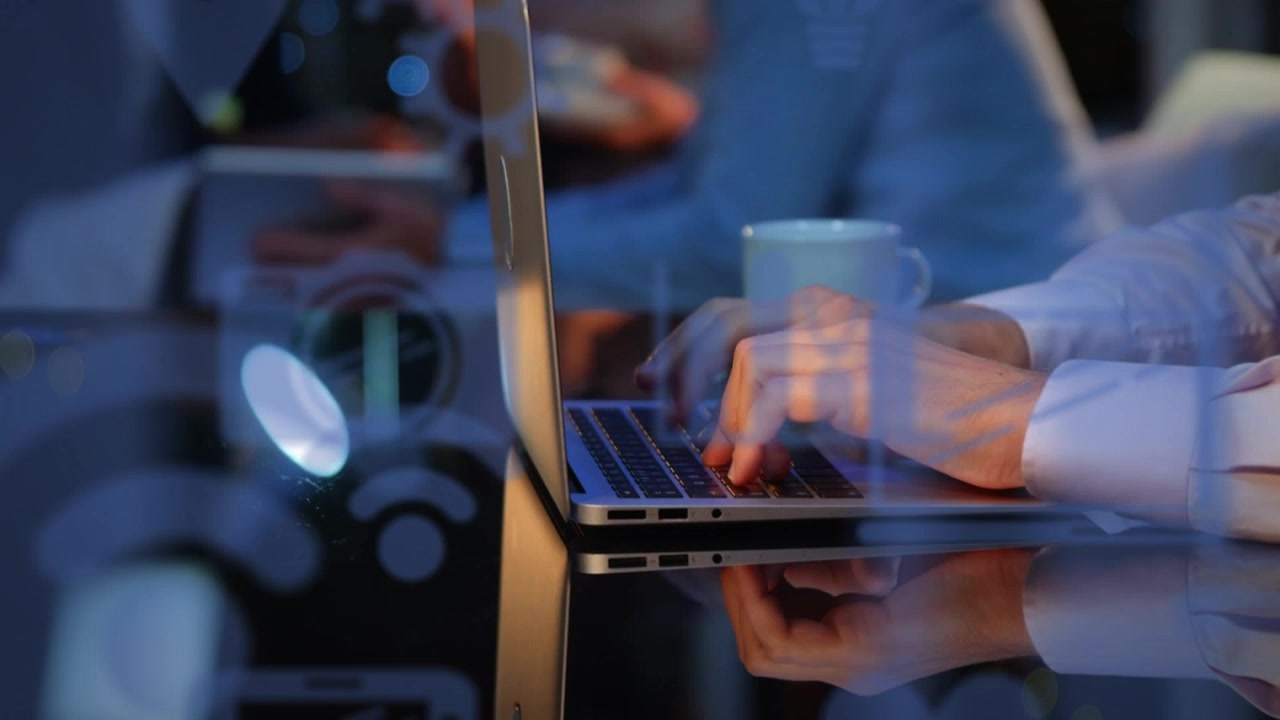 Close-up of Hands Typing on Laptop Keyboard with Digital Interface Reflections