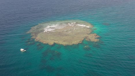 scuba dive tour boat anchors off large reef island in red sea jeddah saudi arabia, aerial orbit