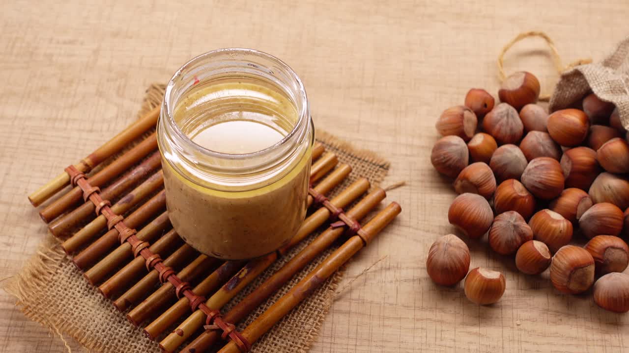 Burro di Nocciole Fatto in Casa in Barattolo con Nocciole Fresche su Tavolo di Legno