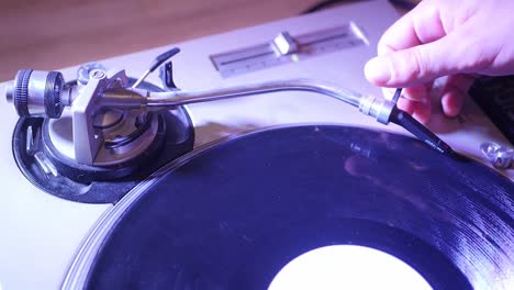 dj placing black vinyl on turn table and placing stylus on vinyl to start mixing music