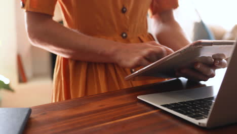 mujer caucásica usando una computadora portátil y una tableta digital en casa
