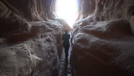 vista posterior de una mujer saliendo de un túnel oscuro a la luz, cámara lenta