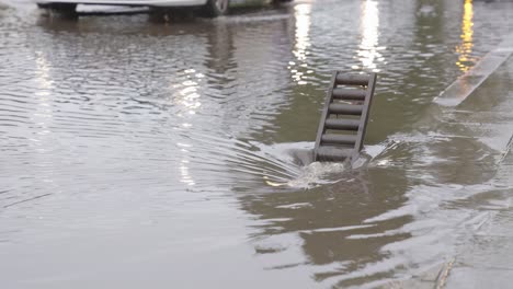 el agua de lluvia de la carretera inundada drena en el sistema de alcantarillado mientras el tráfico circula por las calles de la ciudad