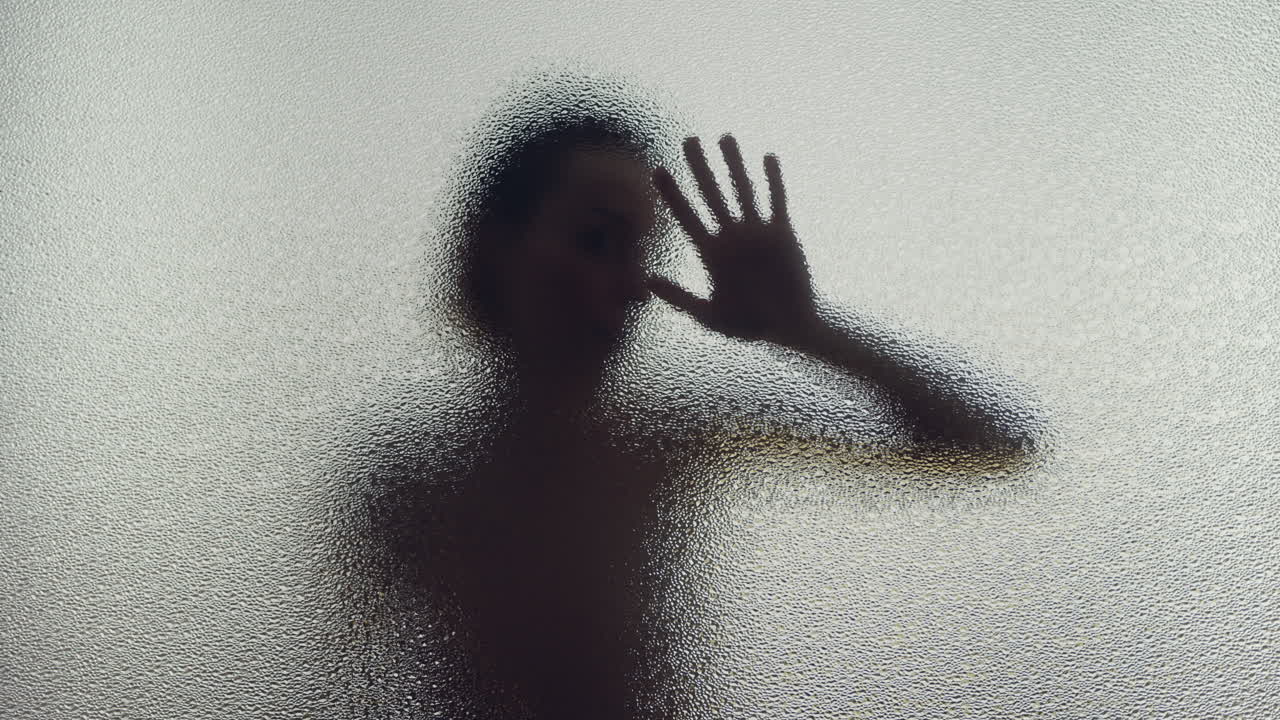 A female silhouette behind the frosted glass moves slowly
