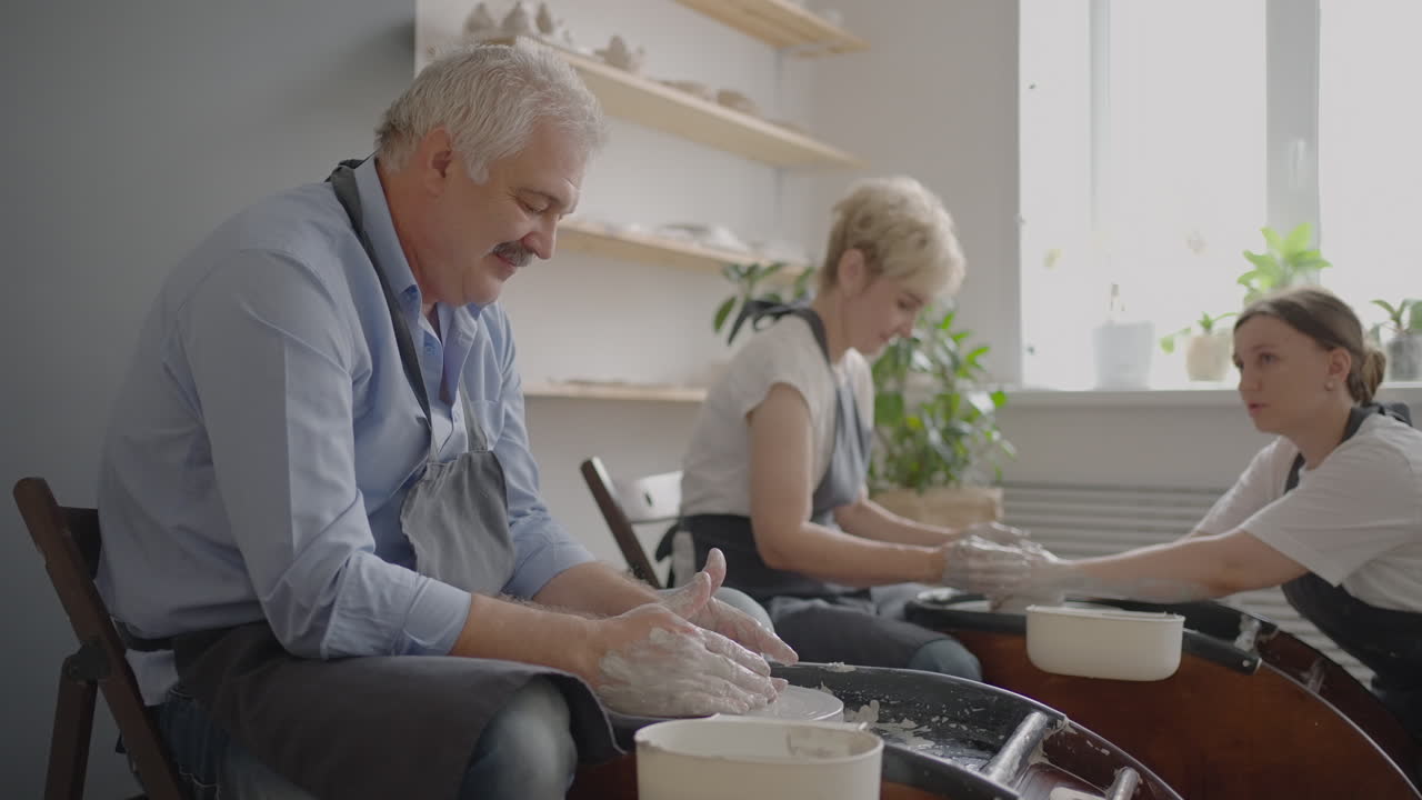 Una giovane donna insegna ceramica a un gruppo di donne anziane e a un uomo di 60-70 anni. Attività per anziani