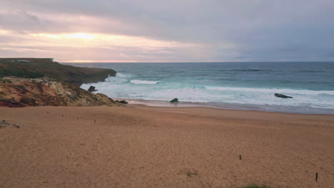 coastal landscape lit sunset light with ocean waves gently washing sandy beach.