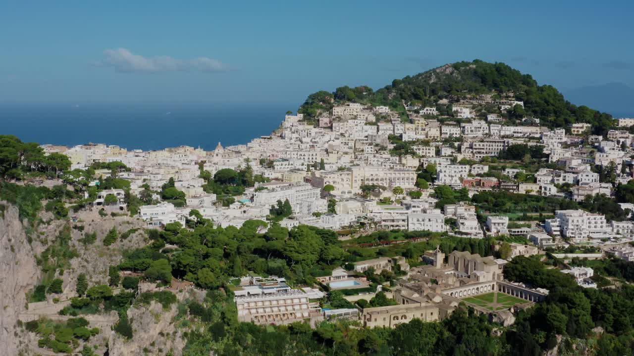 Aerial Drone View Flying Towards a Famous Travel Destination Town in Capri Island with White Buildings Located on Top of Italy's Most Renowned Rocky Limestone Island in the Mediterranean Sea