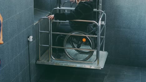 woman with disabilities in a wheelchair climbs stairs on a mechanical lift.