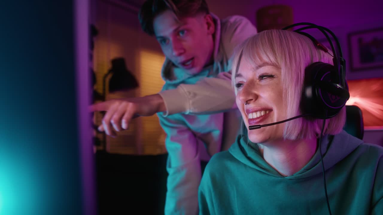 Weiße Frau spielt nachts auf einem Desktop-PC und ihre Freundin unterstützt sie