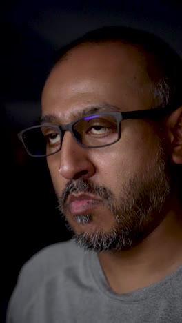 close up of a south asian programmer working at night, the reflection of computer screens visible in his glasses
